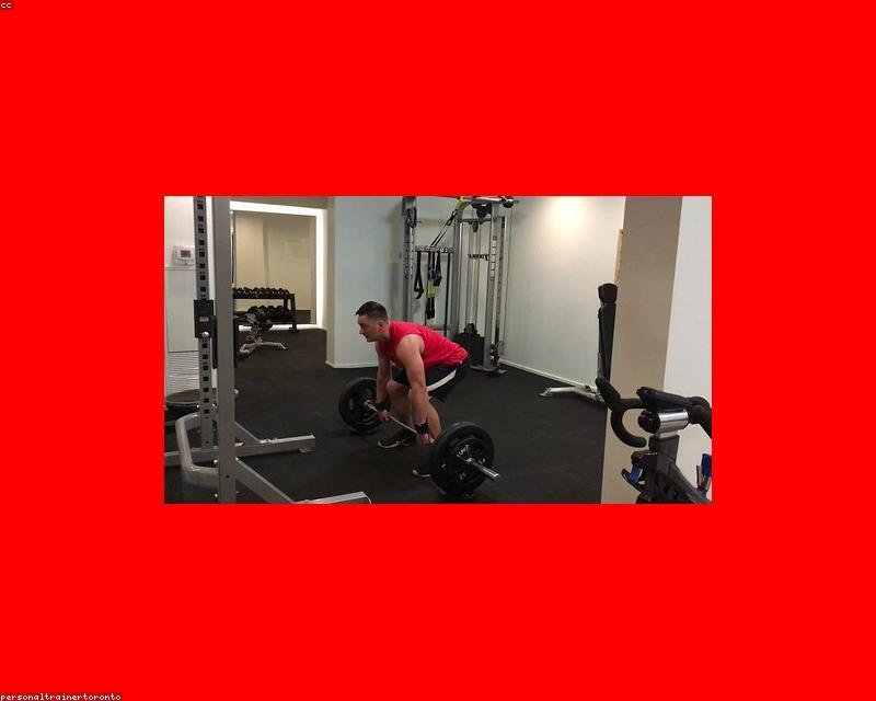 Coach reviewing a lifter's deadlift setup with a loaded bar on a gym platform